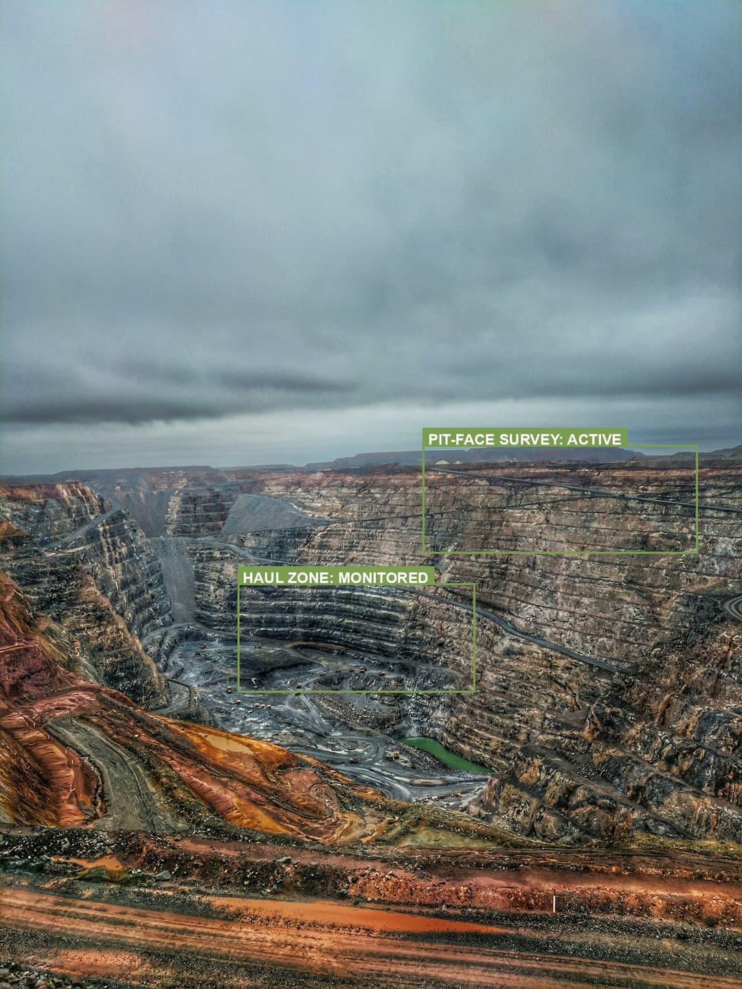 Aerial view of a vast open-pit mine annotated with a monitored haul zone and an active pit-face survey